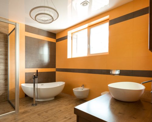 interior of bathroom in orange and white colors with bathtube, sink and bidet
